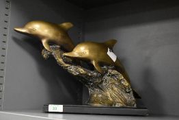 A 20th Century brass dolphin sculpture featuring two dolphins leaping over waves, raised upon a
