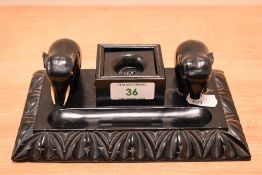 An Indian ebonised desk stand, having a central inkwell flanked by two moulded elephants and