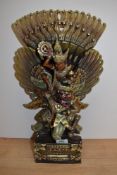 A 20th Century carved wooden study of a Balinese deity, hand painted and heightened with gilding,