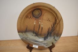 A 20th Century studio pottery plate of Paul Gooderham style, decorated with a stylised landscape