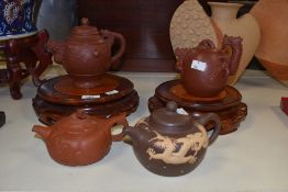 Four Chinese Yixing teapots, each decorated with relief moulded dragon designs, with two circular
