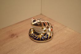 A Royal Crown Derby bone china Frog paperweight having and silver coloured stopper to underside,
