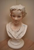 A moulded pottery bust of a young boy, head and shoulders, lightly accented and with painted