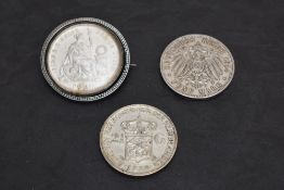 A 1869 Peru One Sol Silver Coin in a brooch mount along with a 1914 Silver Five Mark Coin and a 1938