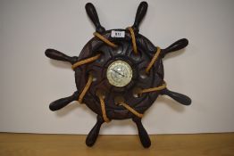 A mid-20th Century stained oak ship's wheel barometer, having a champagne coloured dial and