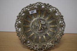 A cast brass pedestal dish, cast with various repeating motifs and central figure, raised on a