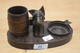 An early 20th Century carved wooden novelty desk stand or smoker's companion, the centre modelled