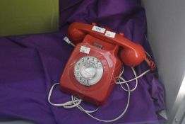 A vintage Kirkcaldy rotary telephone in ruby red.