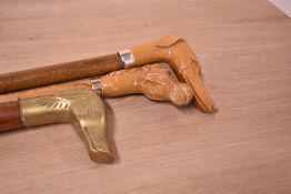 Three walking sticks with greyhound style dog heads two are carved and one is cast brass