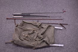 A green canvas frame rucksack containing four leather riding crops