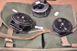 A fishing or game bag containing 3 fly reels A Pridex and Windex by Youngs and a Marvel by Allcocks
