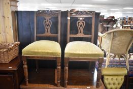 A pair of Victorian oak dining chairs having overstuffed seats and turned legs