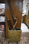 A vintage brass stick stand and contents including sticks and golf clubs