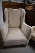 A Victorian Howard style wingback armchair with cream covers