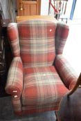 A modern wing back armchair in red tweed upholstery