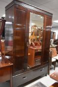 An early 20th Century mahogany mirror door wardrobe, having drawer base
