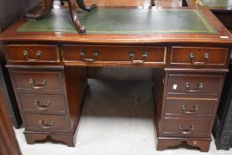 A reproduction mahogany pedestal desk, with inset gilt tooled green leather skiver to the serpentine