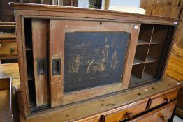 An early 20th century pine storage cupboard with two sliding doors enclosing pigeon holes, one