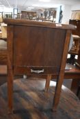 A 20th century walnut sewing cabinet, having a hinged lift-up top opening to reveal the sectioned