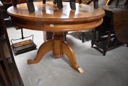 A modern circular pine pedestal table, having large central turned support issuing three down