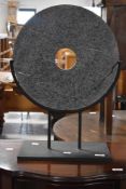 A decorative turned stone sculpture, of curcular form with central circular aperture, raised on a