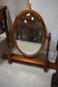 A reproduction mahogany dressing table top swing mirror, of oval form, pivoted between turned