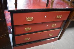 A red and black painted chest of three drawers, 82cm high