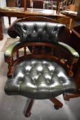 A reproduction deep-buttoned green leather and mahogany swivel tub-form office chair, seat height