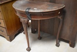 A Victorian mahogany demi-lune card table, of traditional design with moulded and carved foliate