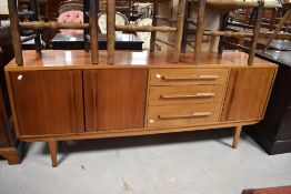 A 1960s/70s craftsman made teak sideboard, with an arrangement of cupboards and drawers, raised on