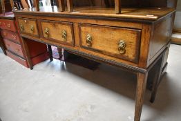 A late Georgian oak dresser base, the oblong top above three crossbanded drawers, each with later