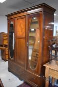 An early 20th century inlaid mahogany mirror door wardrobe, with moulded and inlaid cornice over the