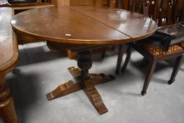 A late 20th century oak draw-out dining table, of circular form with concealed folding central leaf,