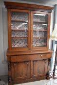 A Victorian figured mahogany bookcase over cupboard, the lower stage with long plain frieze drawer