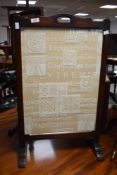 A 1940's oak fire screen with later machine embroidered Latin text panel 75cm