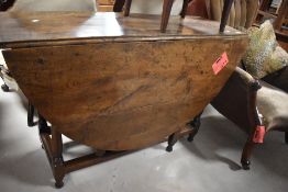 A 19th century oak gate-legged dining table with demi-lune flaps and block and turned supports