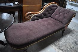 A Victorian chaise longue, upholstered in purple patterned material, the raised and scroll shaped