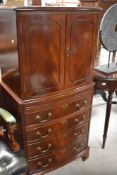 A reproduction mahogany drinks cabinet, the rectangular bow-fronted top over two panelled doors,