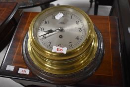 A Bankers of Kensington brass bulkhead clock, of circular form and mounted to a moulded circular