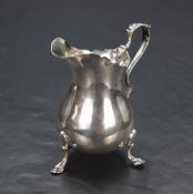 A George V silver cream jug, having a Chippendale style rim with a narrow spout opposed by a