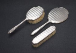 A cased Elizabeth II silver mounted vanity set, comprising a hair brush, a clothes brush and a