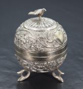 An Eastern white metal trinket box, of circular form having a bird form finial with embossed