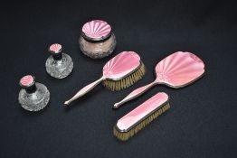 A George V pink guilloche and silver mounted vanity set, comprising a hair brush, clothes brush,