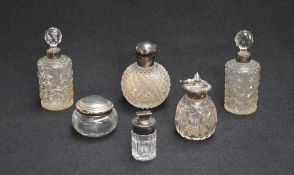 An assortment of silver mounted and capped cut glass vanity table wears, comprising scent bottles