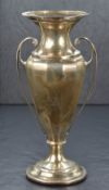 A George V silver vase, having a flared rim and canted body with scroll handles, raised on a