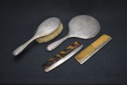 A George V silver mounted vanity set, comprising a hair brush, comb and mirror having engine