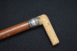 An early 20th century white metal mounted walking stick, the wooden cane with white metal ferrule