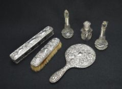 An Edwardian silver mounted mirror having embossed floral and scroll decoration, along with a silver
