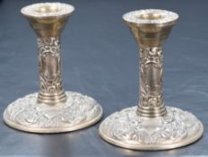 A pair of Elizabeth II silver candlesticks, of traditional form having embossed scroll decoration to