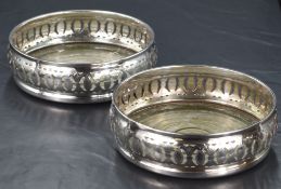 A pair of Elizabeth II silver wine coasters, having decorative pierced and engraved sides with